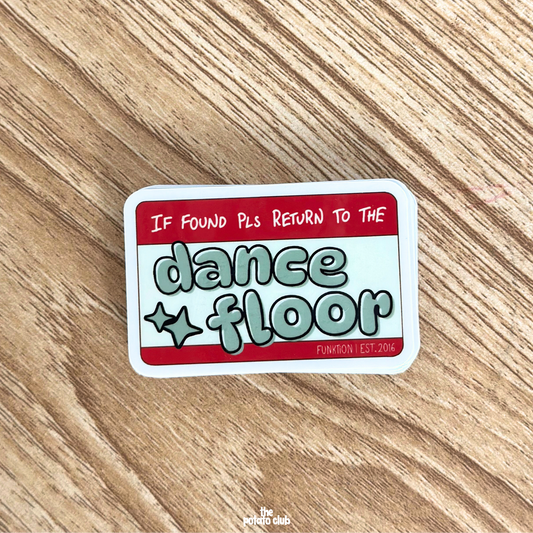 Sticker with 'If found pls return to the dance floor' text on a wooden surface