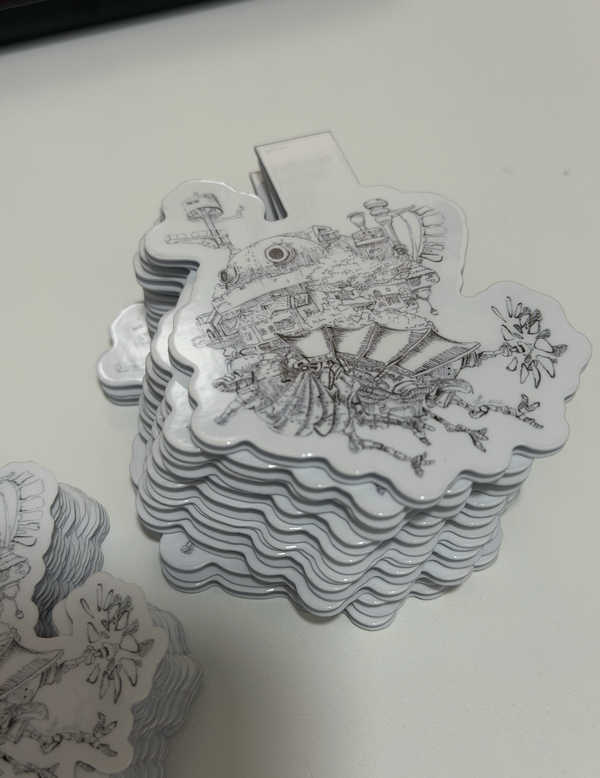 A stack of hand drawn magnetic bookmarks featuring black line art illustrations of steampunk-themed characters and machinery, photographed on a light gray surface.