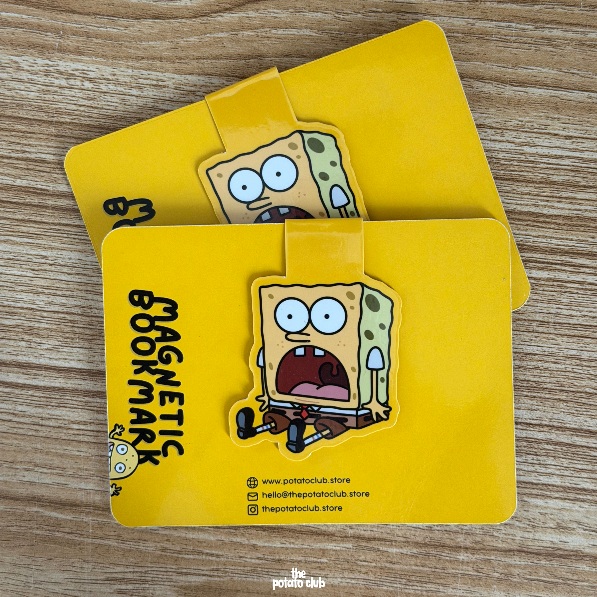 Two yellow magnetic bookmarks with cartoon characters on a wooden surface